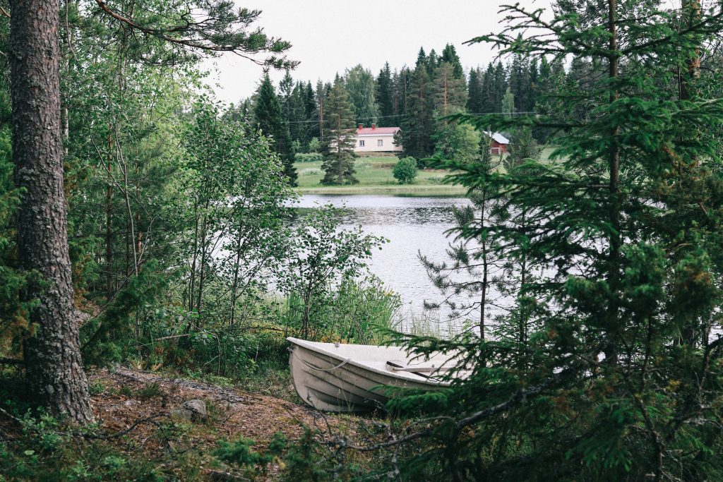 Our jetty at our cottage via Mokkiavain Cottages. A small white boat pulled ashore one of the Finnish lakes in Tampere.